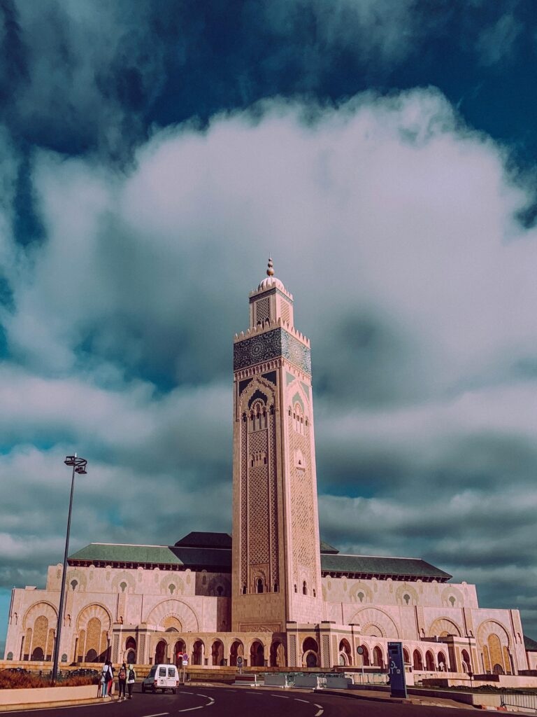 The Hassan II Mosque in Casablanca with its towering minaret set against a dramatic cloudy sky.