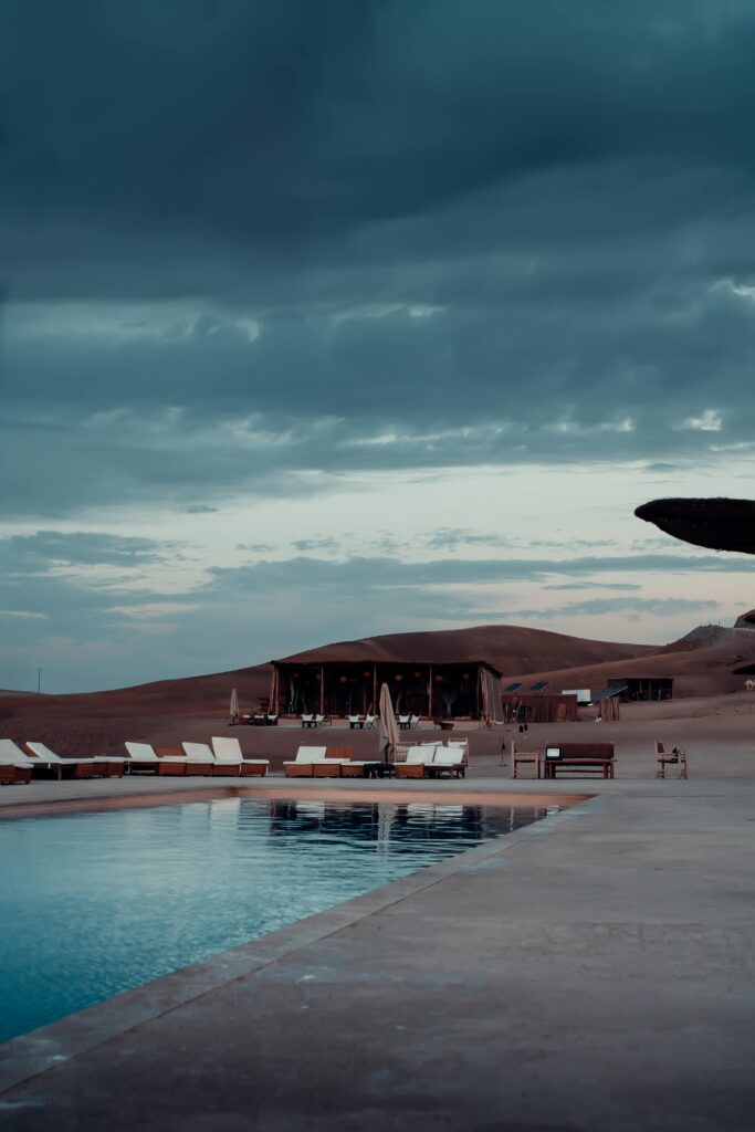 Tranquil desert scene with a luxury poolside view at a glamping resort in Agafay, Morocco.
