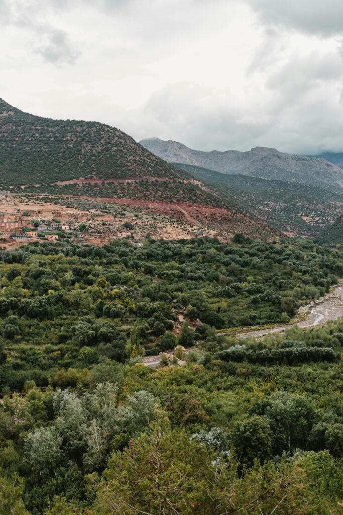 Explore the lush greenery and majestic Toubkal Mountain Range under a dramatic overcast sky.