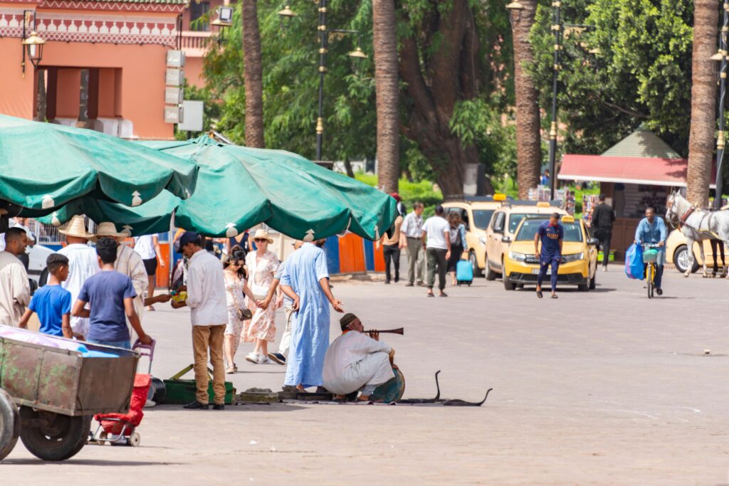 pexels-photo-25489943-25489943 A bustling scene at Jemaa el-Fnaa square in Marrakech with local snake charmers and tourists