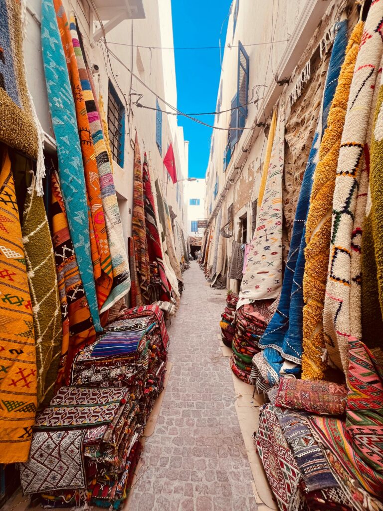 Colorful traditional rugs in a bustling Moroccan souk, perfect for travelers.
