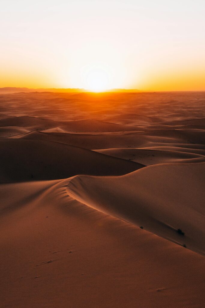Golden sunrise illuminating the vast dunes of the Sahara Desert in Morocco.
