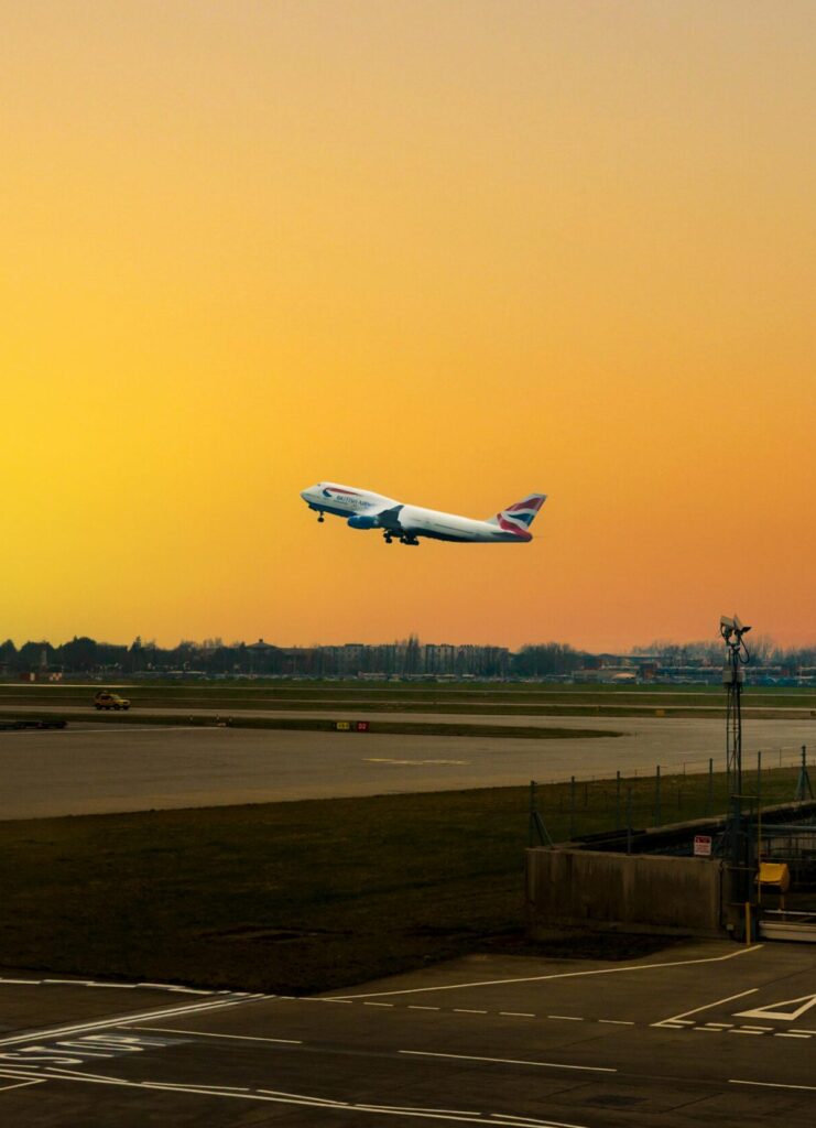 pexels-photo-6604557-6604557 Airplane ascending during sunset at Heathrow Airport, capturing the vibrant sky.